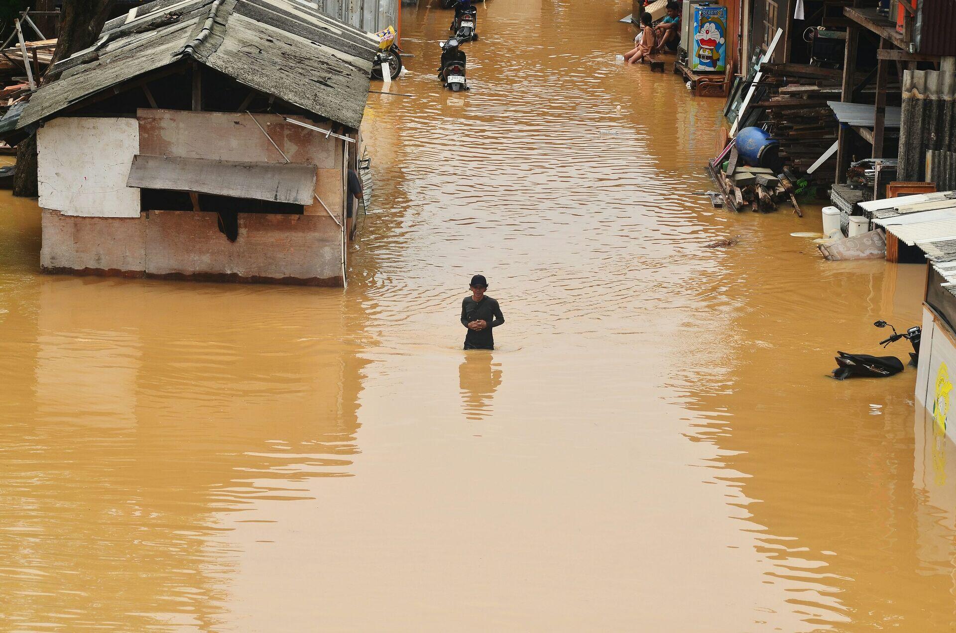 People in a small rescue boat moving through floodwaters past partially submerged houses