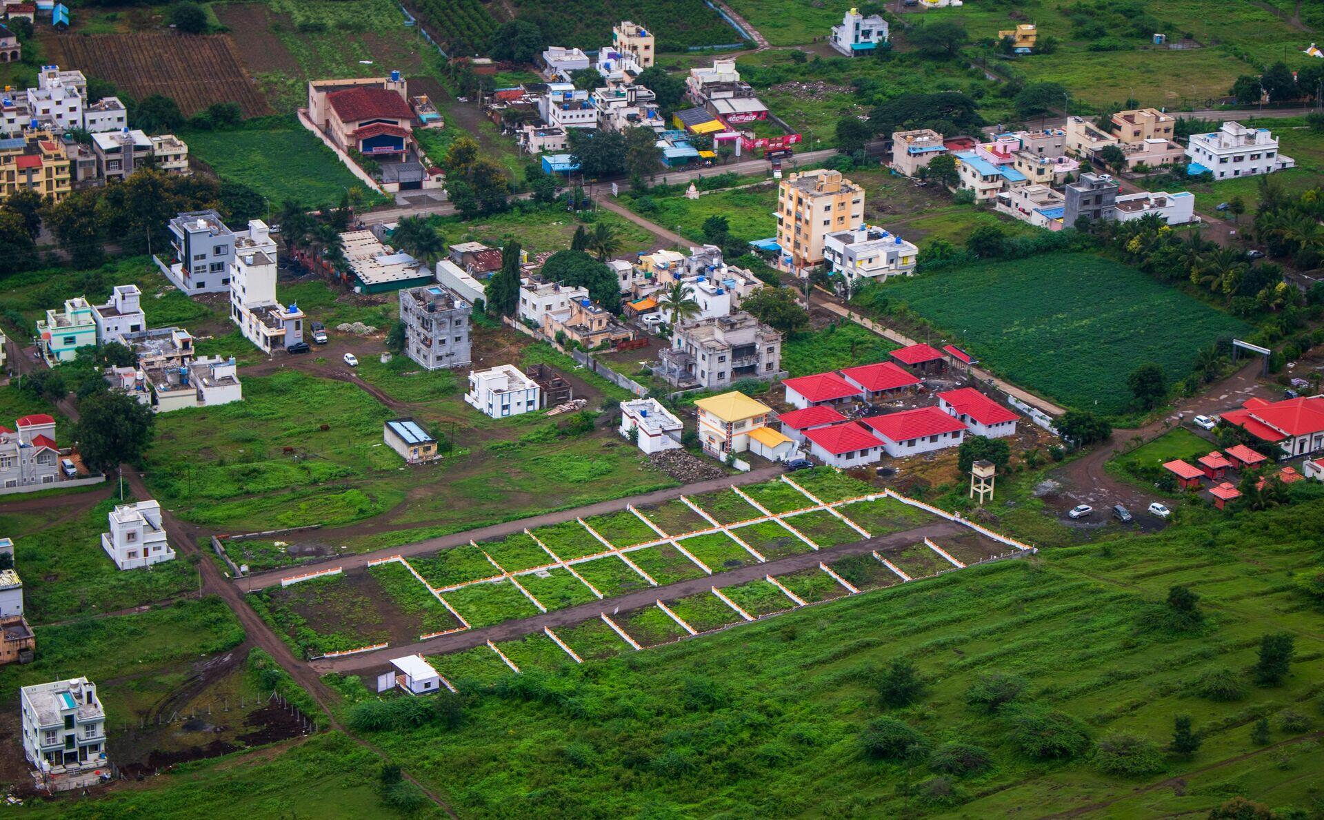 Land surveyor with GPS equipment marking a plot boundary while community members observe in a dense urban neighbourhood