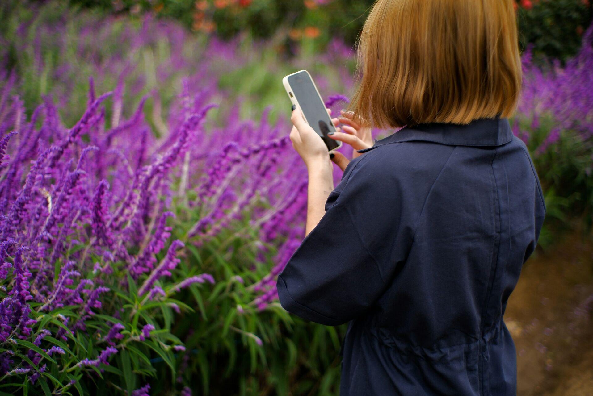 Person in rural setting holding a feature phone outdoors, reading a message