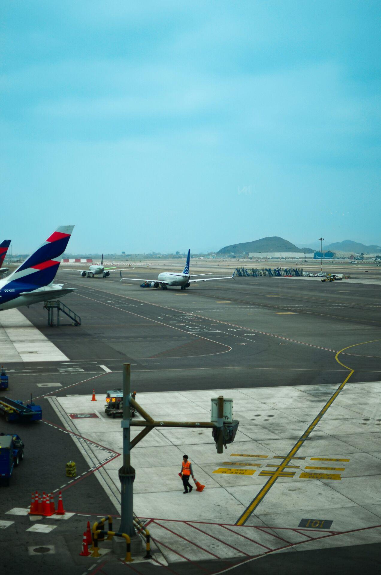 Workers on an airport apron with aircraft and terminal building in background