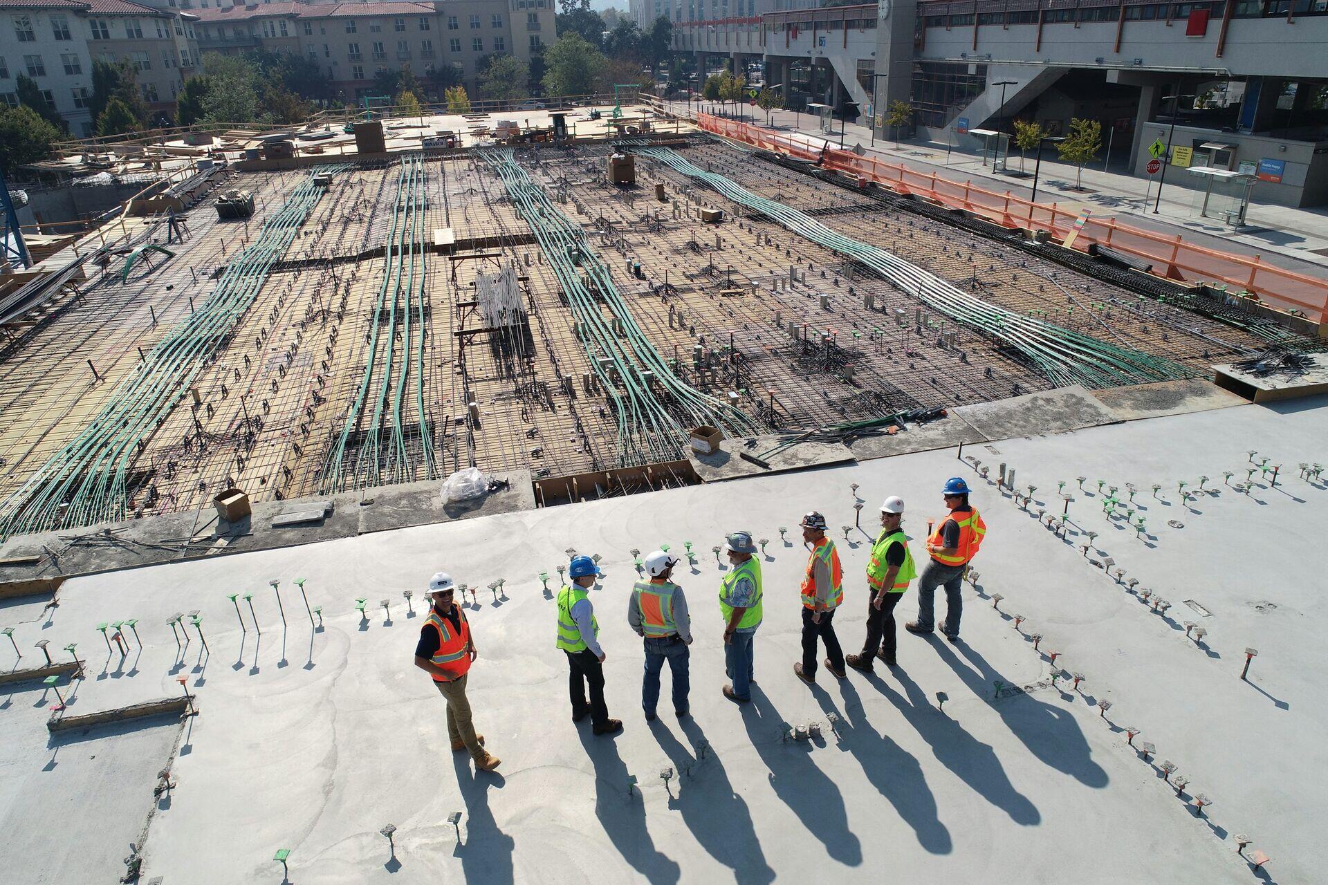 Construction workers surveying a utility corridor through open landscape