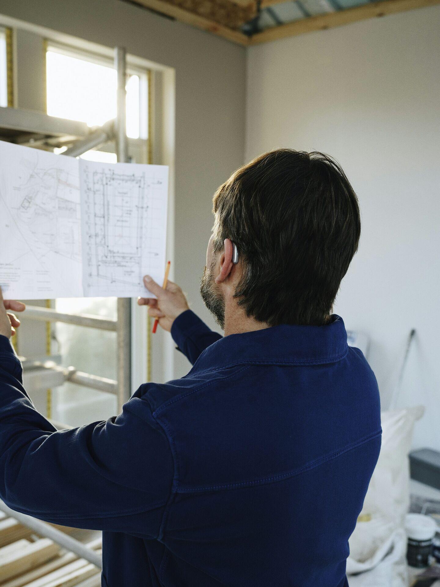 Two engineers on a construction site looking at a laptop displaying a 3D infrastructure model