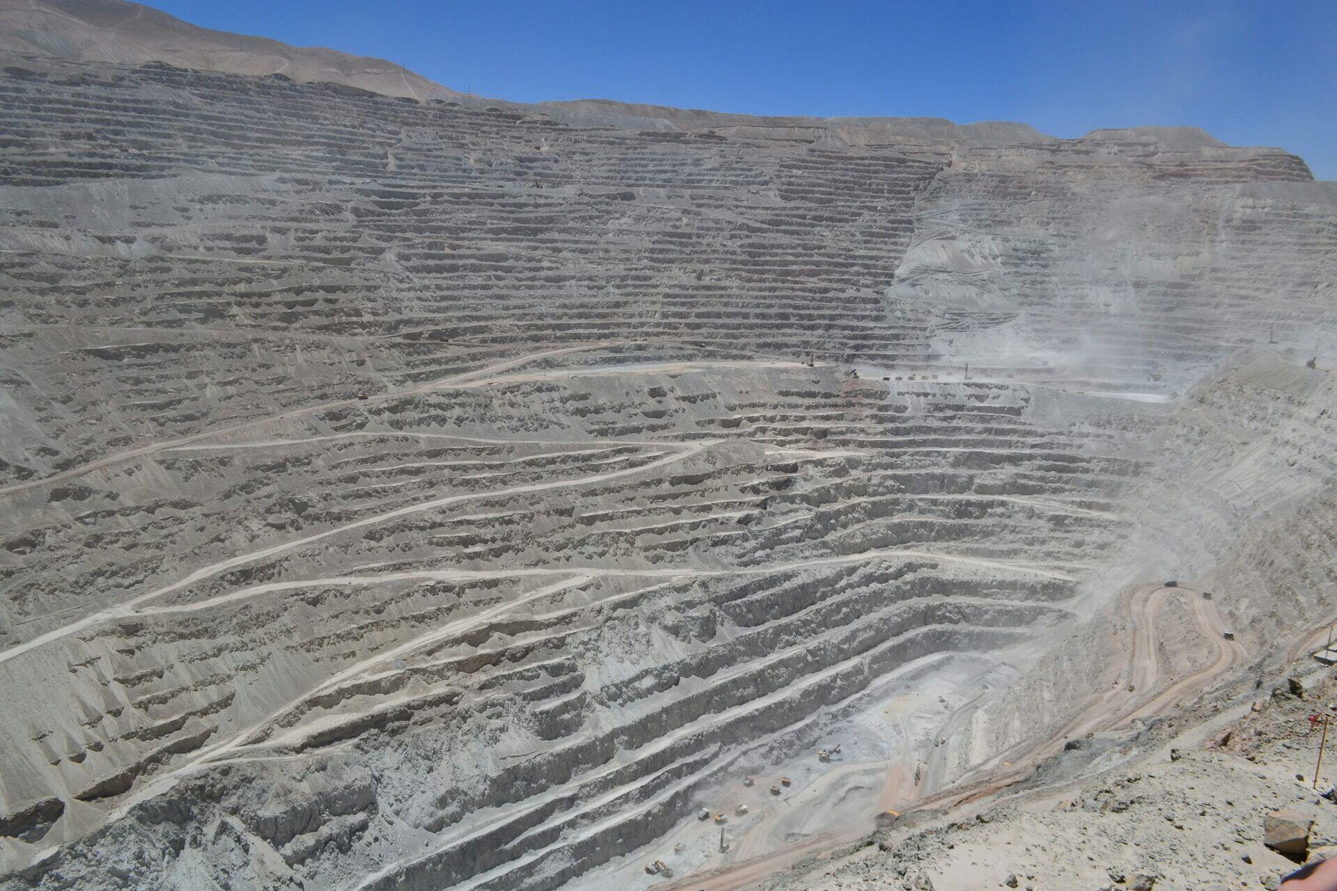 Mine workers in hard hats examining equipment and data at an open-pit mining operation