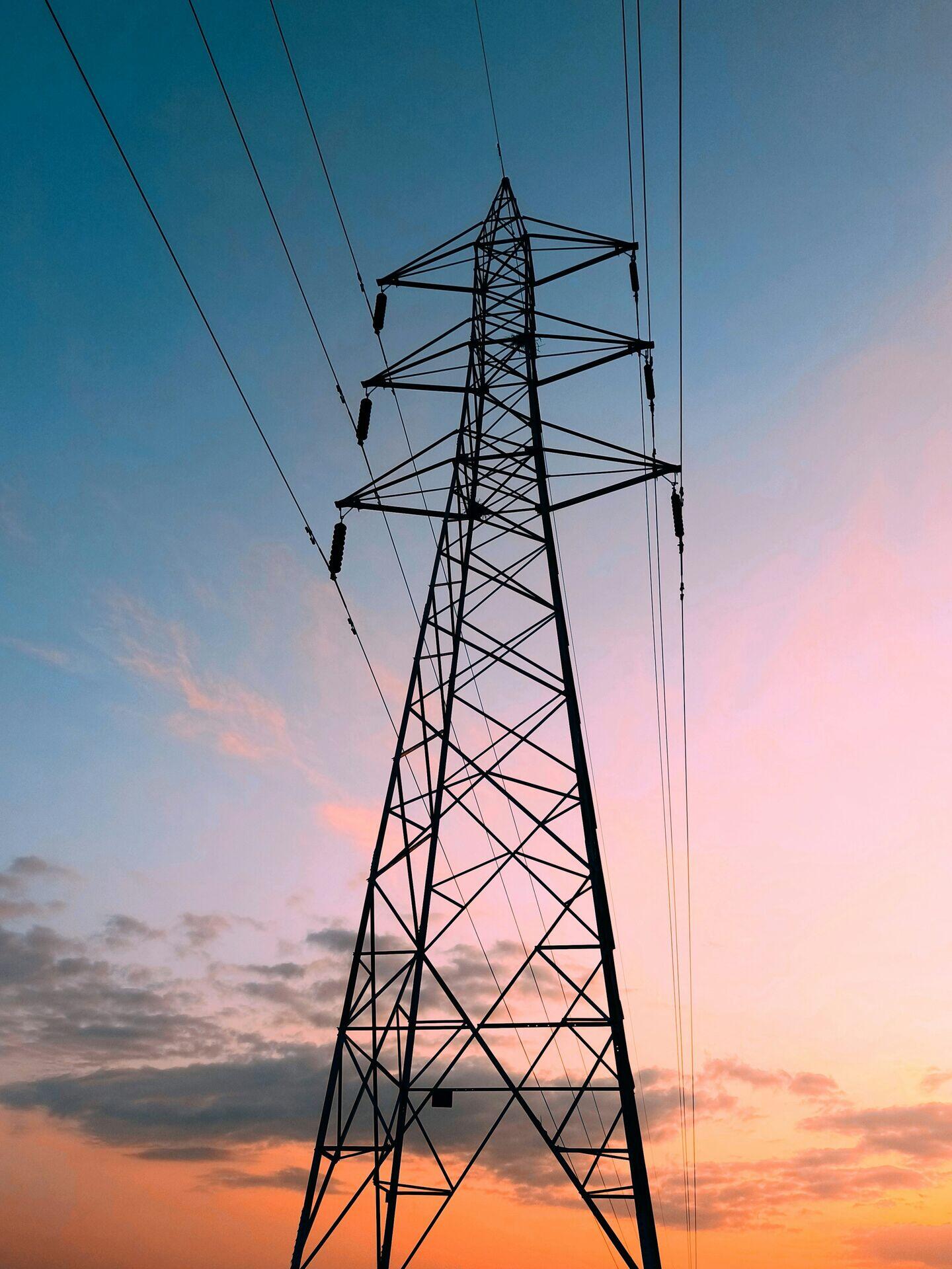 Utility worker in high-visibility vest inspecting overhead power lines on a rural road