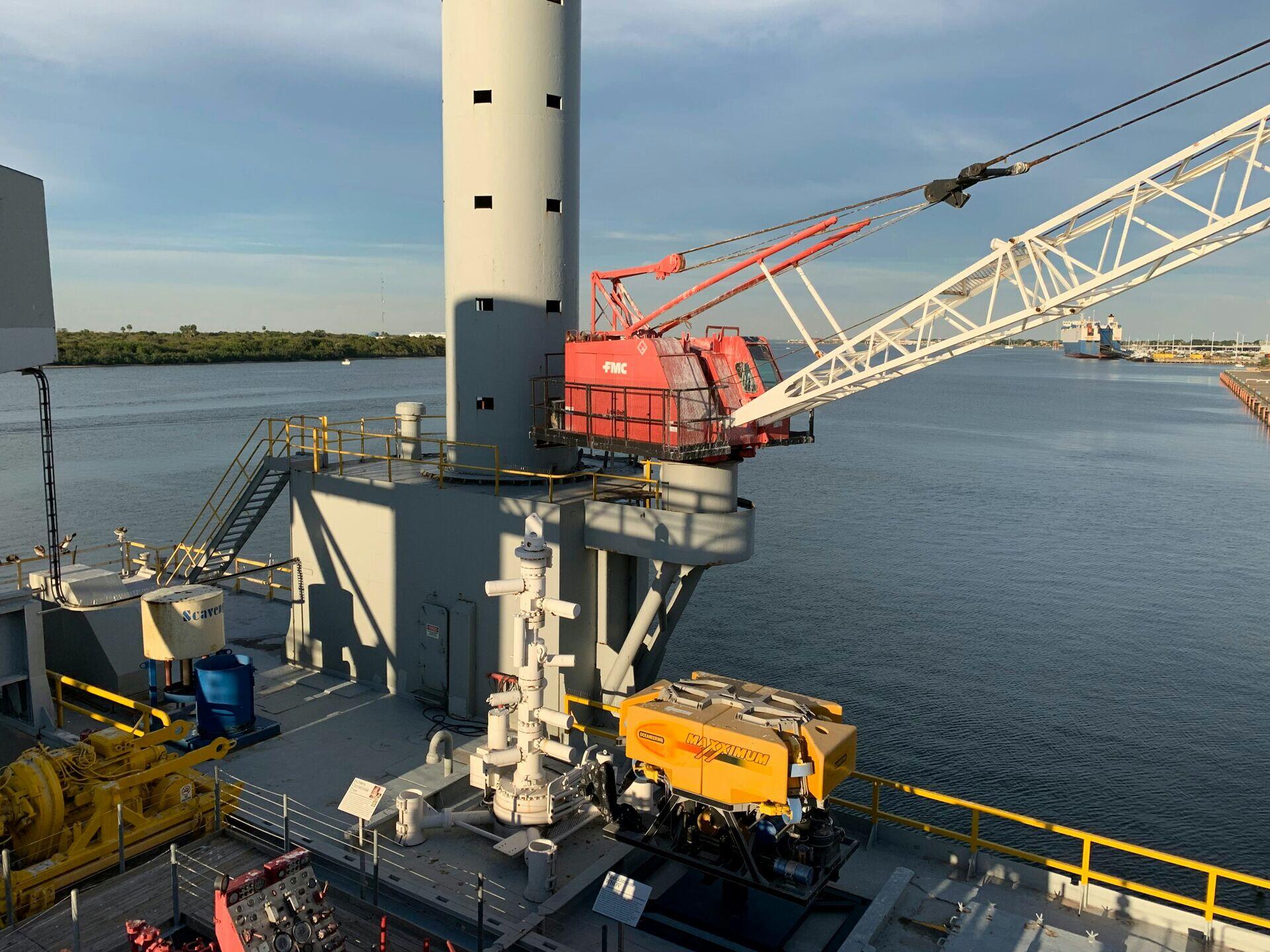 Workers in hard hats on an offshore oil or gas platform deck with industrial equipment and open sea in background