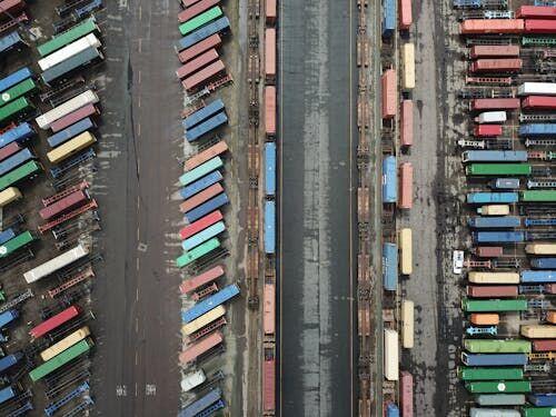 Workers in high-visibility vests scanning cargo containers at a busy port