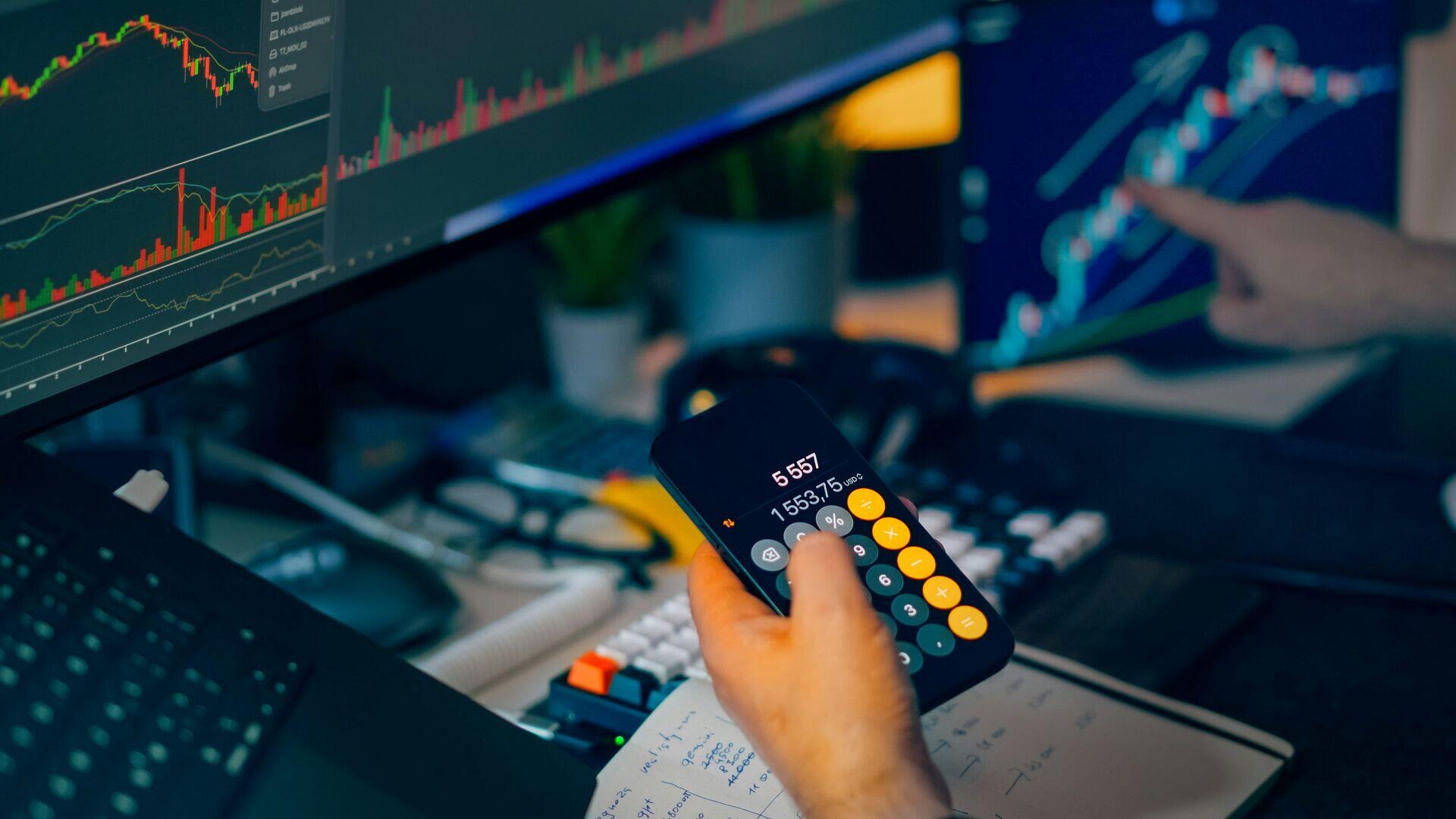 Analyst at a desk reviewing multiple data screens showing charts and trade figures in an urban office