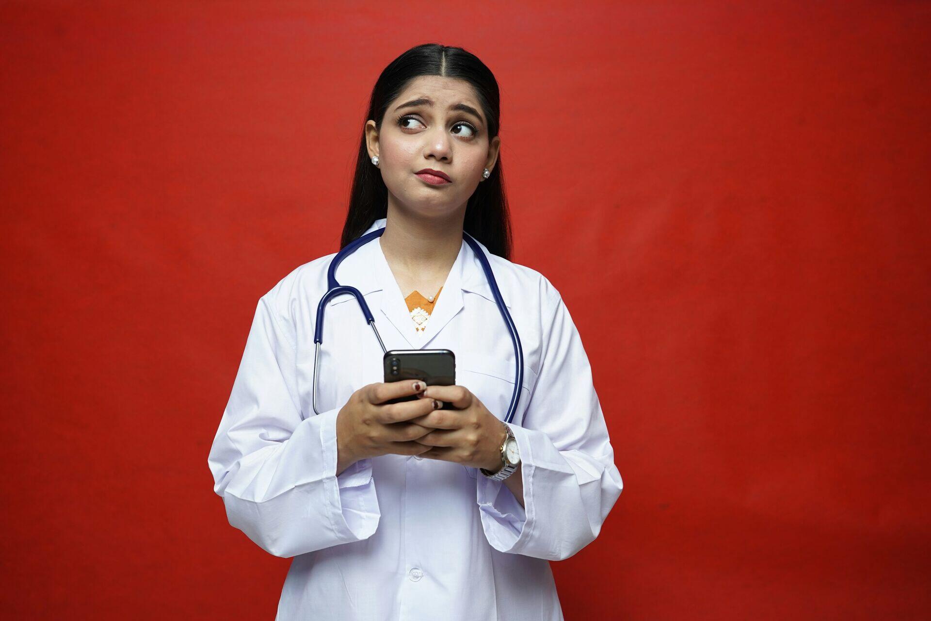 A health worker in a rural African village recording patient data on a mobile device outside a small clinic