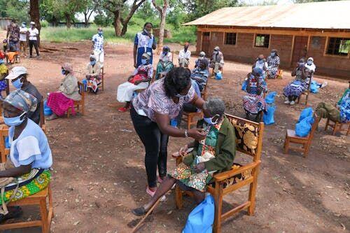 Community health worker with tablet interviewing a family outside a rural home