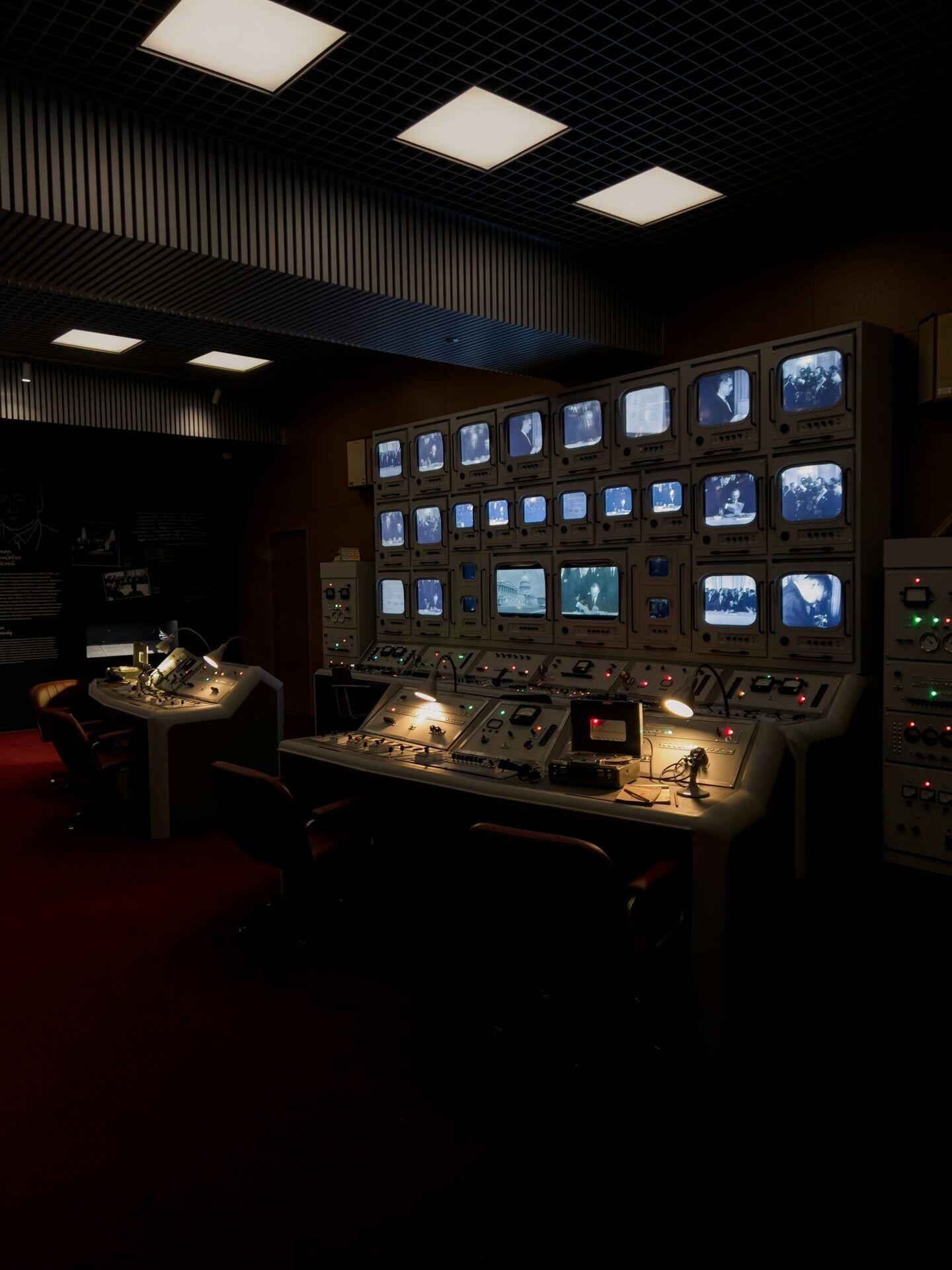 Engineers seated at illuminated monitoring stations watching orbital tracking displays in a darkened control room
