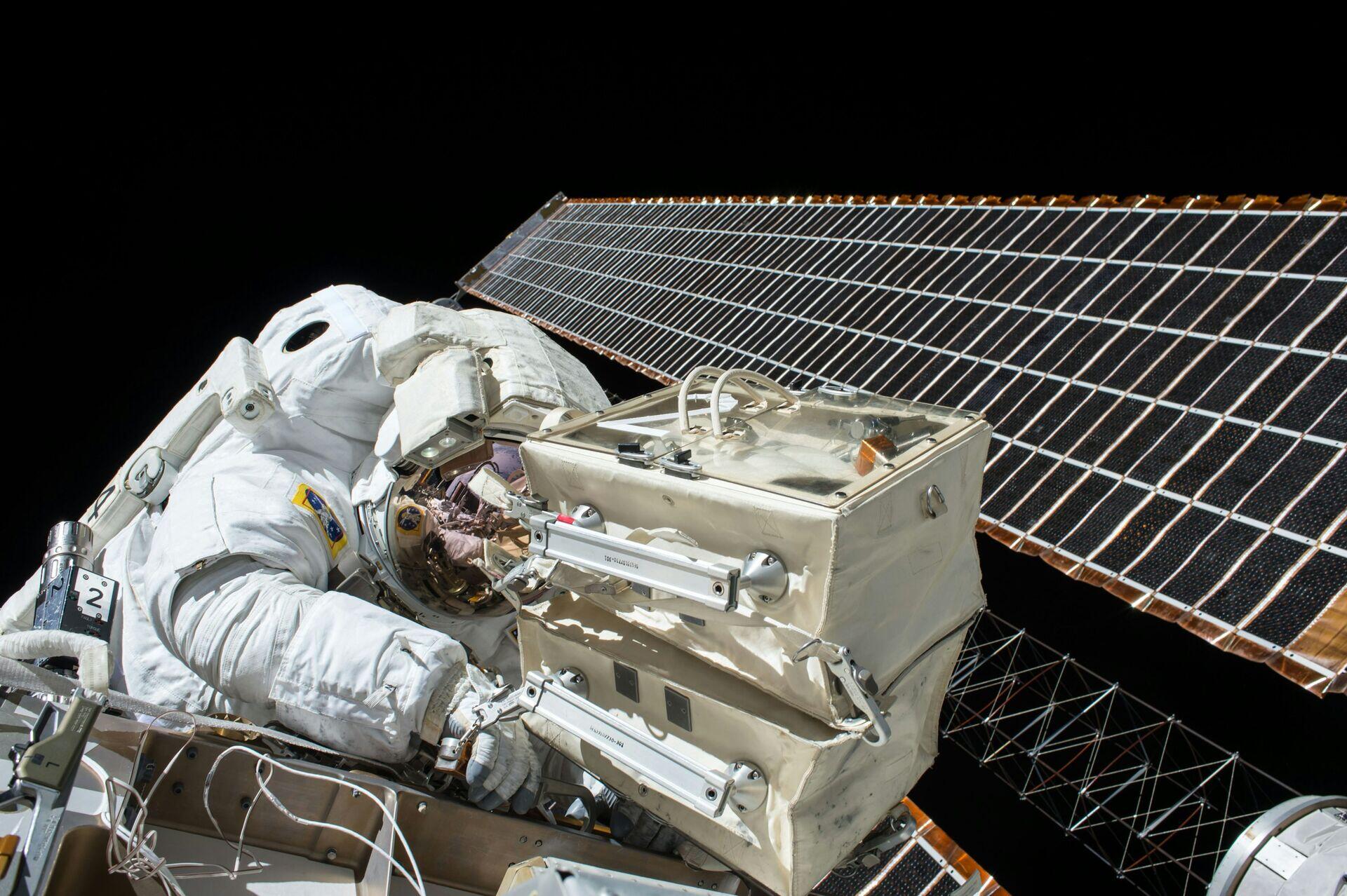 Engineers in white cleanroom suits inspecting a large satellite component in a high-tech facility