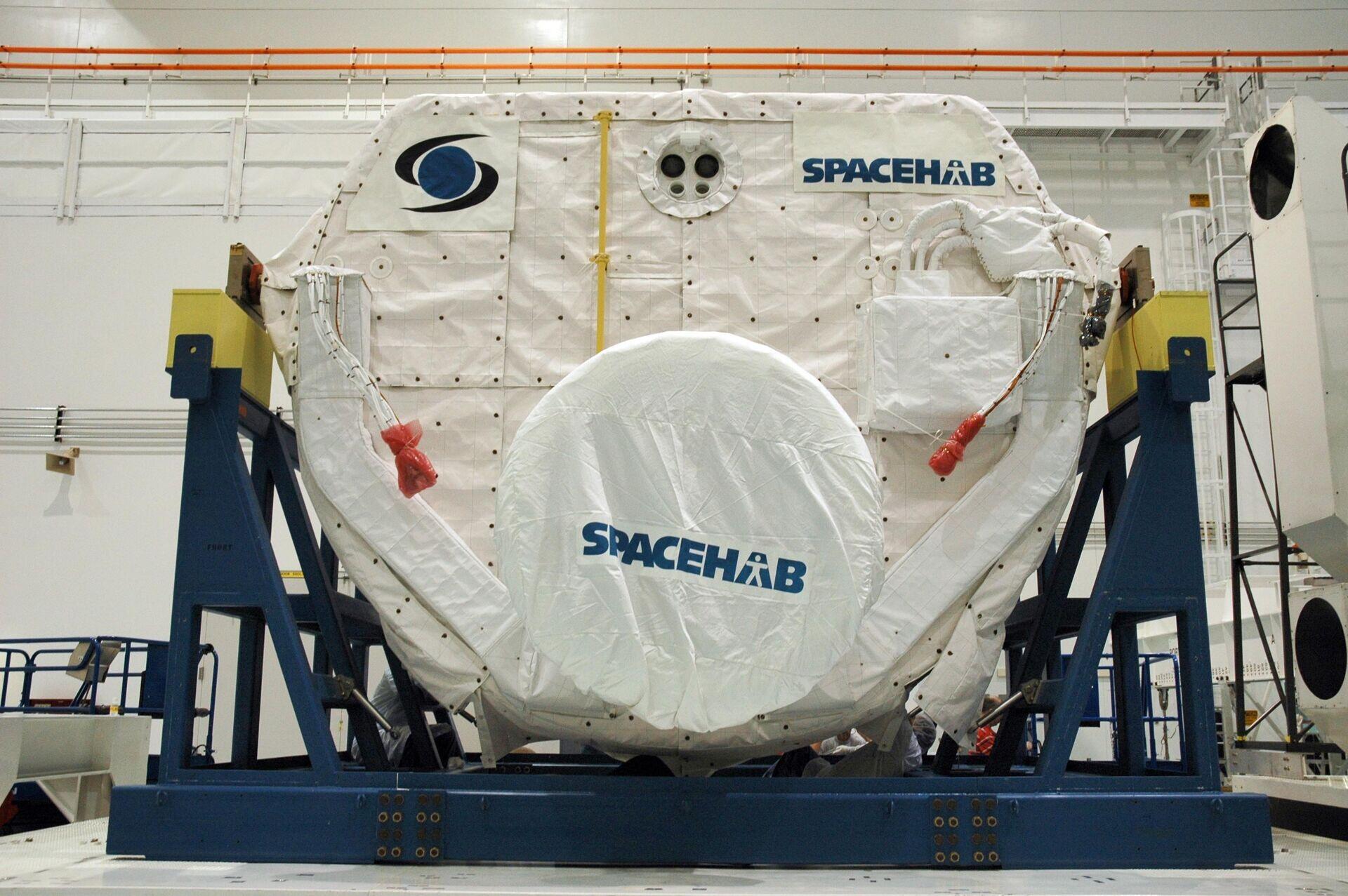 Two technicians in white cleanroom suits inspecting electronic hardware mounted inside a satellite structure
