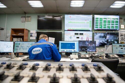 Technician seated at a multi-screen console inside a satellite ground operations center