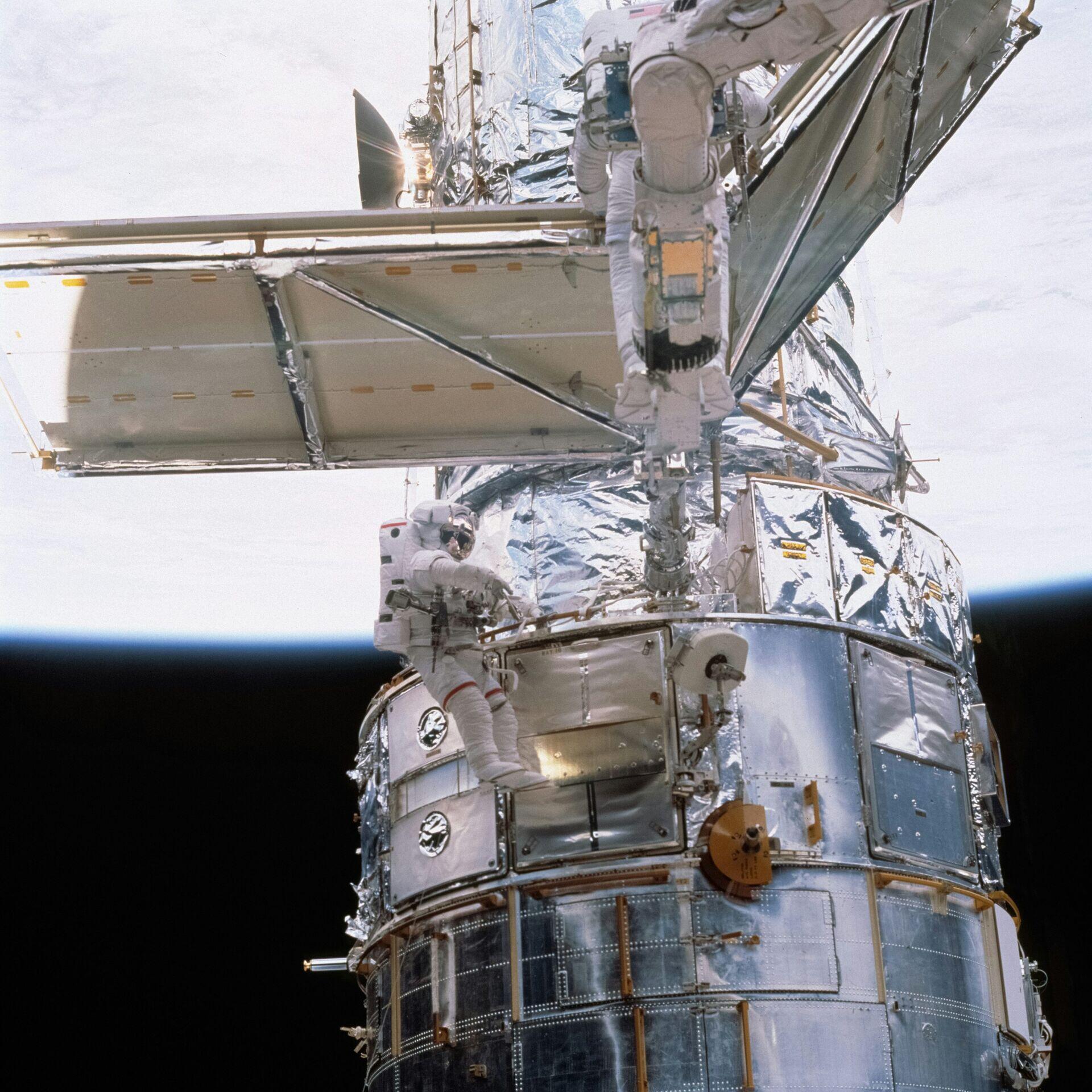 Astronauts at workstations inside a space station module with Earth visible through a porthole window