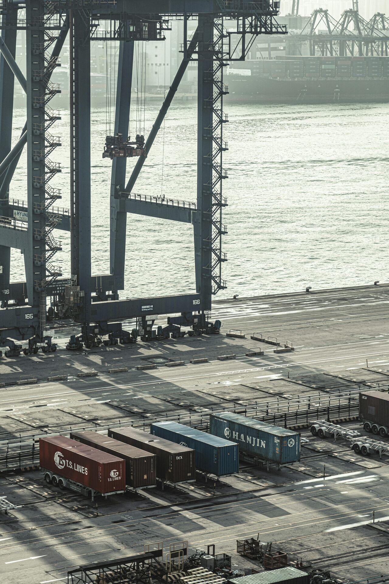 Workers and cranes loading cargo containers onto a large ship at a busy commercial port