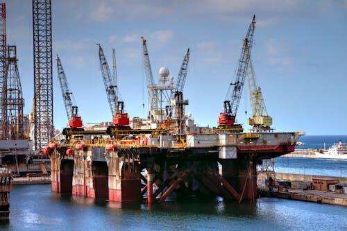 Workers in hard hats and safety gear inspecting equipment on an offshore oil and gas platform at sea