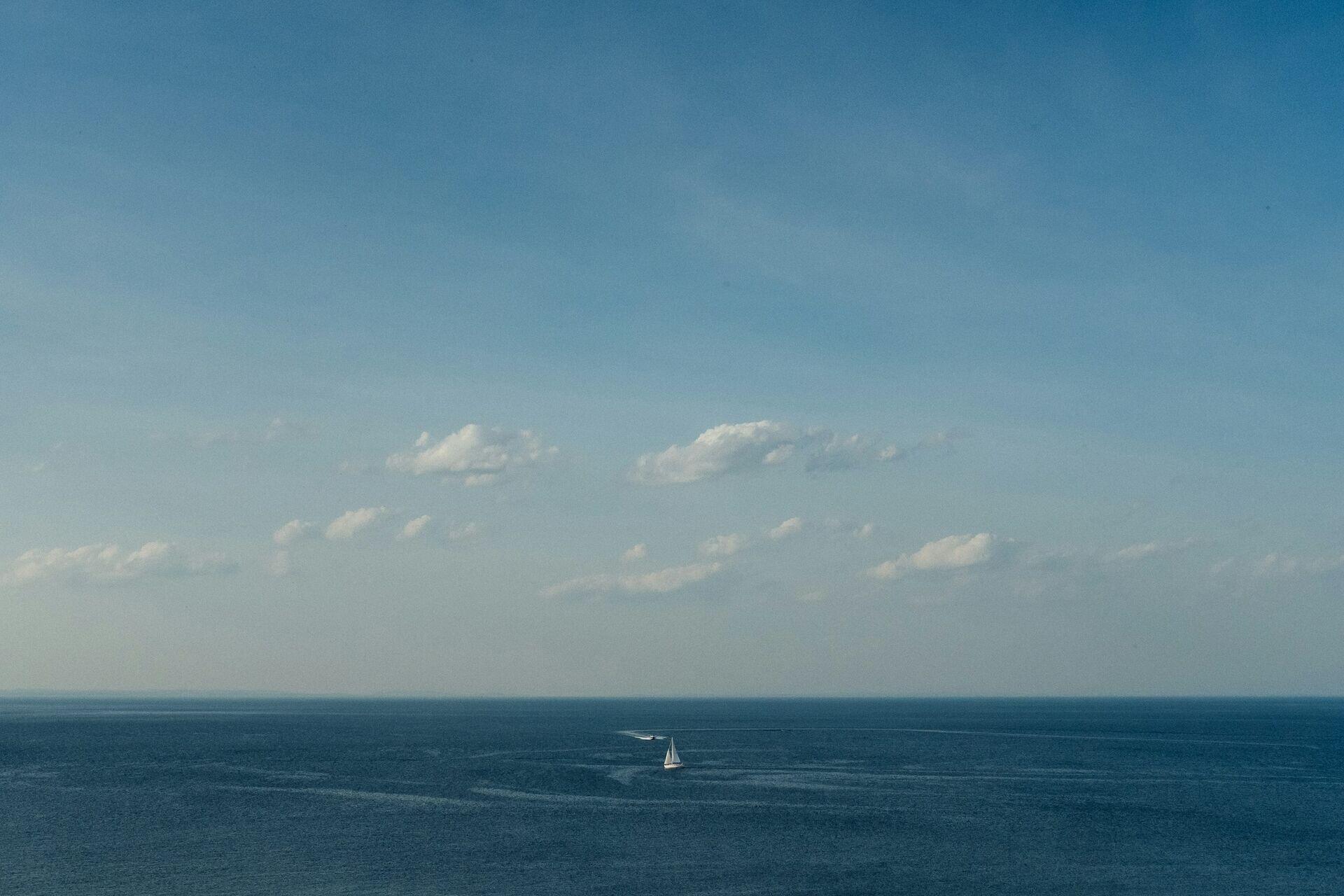 Small wooden fishing boats on open ocean waves near a coastal village