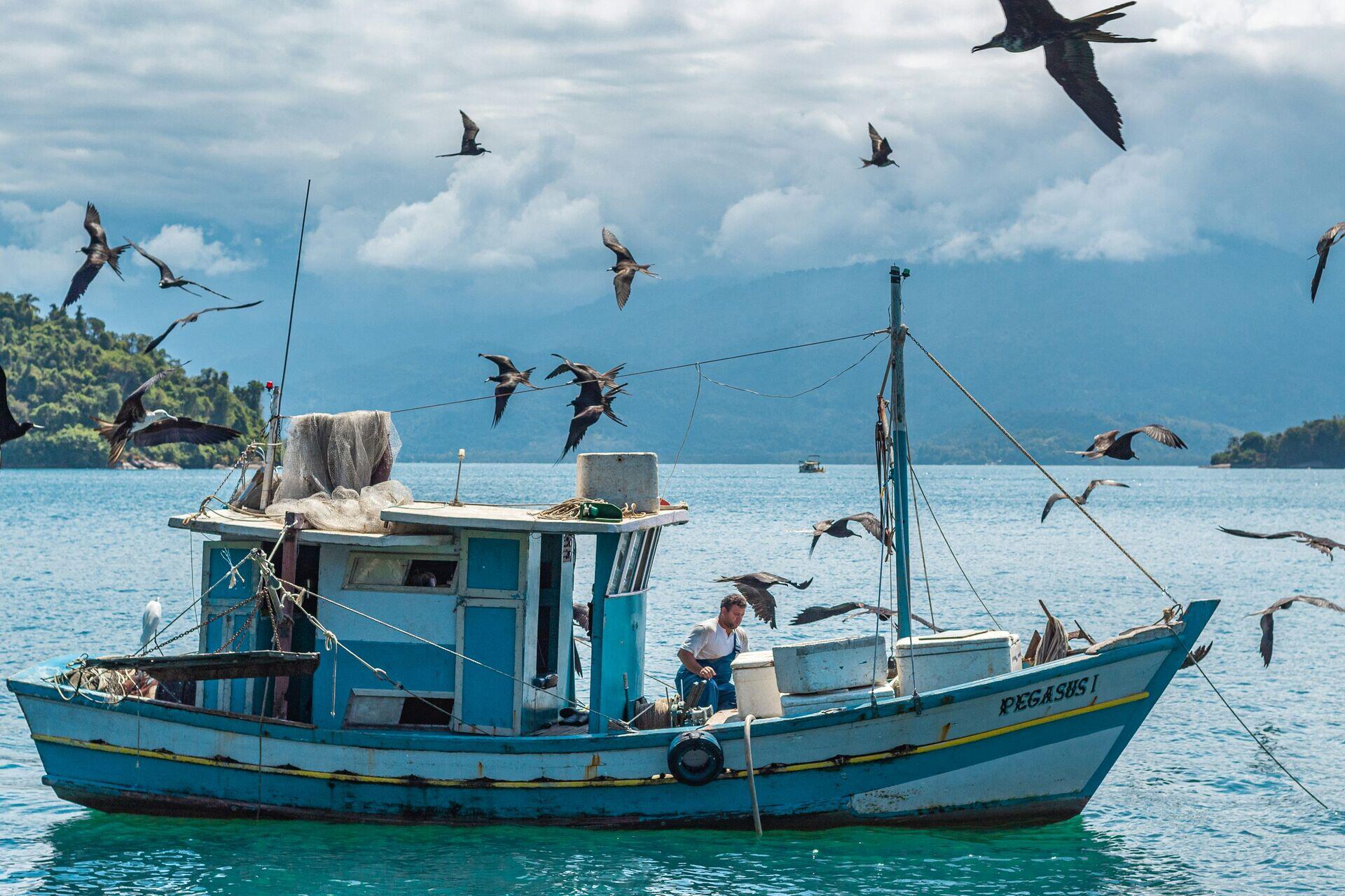 Coast guard officers in uniform on a patrol boat alongside a smaller fishing vessel at sea