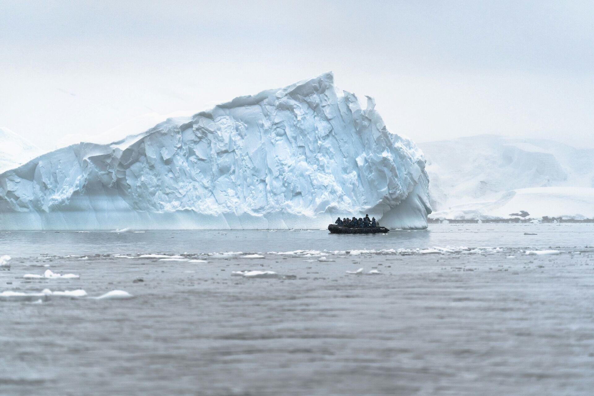 Two people on a snowmobile crossing a vast expanse of sea ice in Arctic conditions