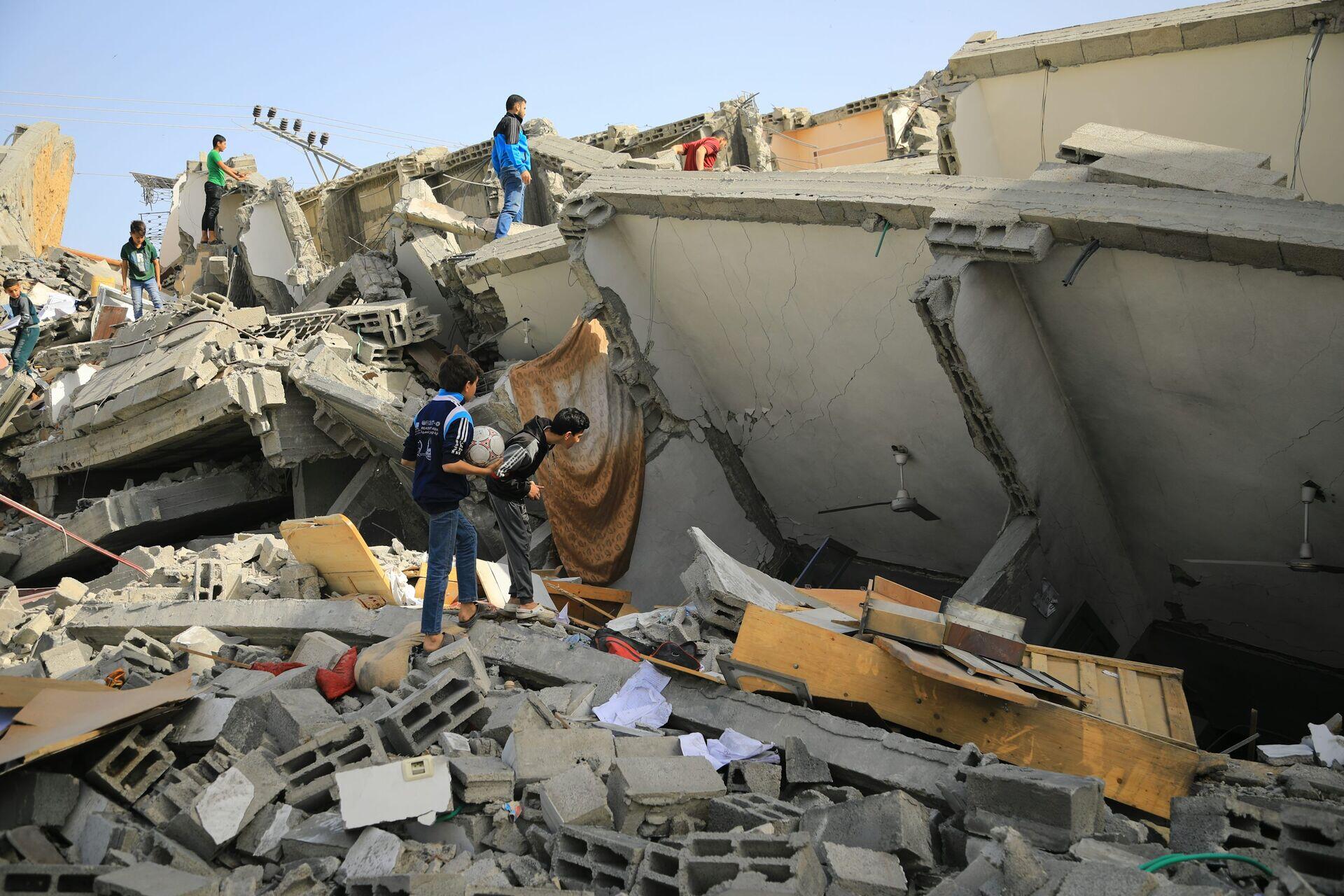 Rescue workers in orange helmets searching through rubble of a collapsed concrete building after an earthquake